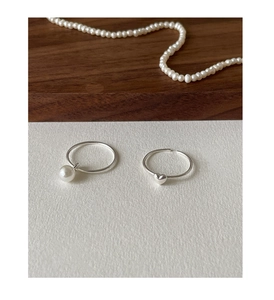 Detail of 925 sterling silver rings featuring a delicate pearl pendant and heart shape