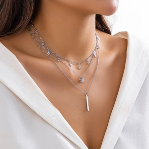 Close-up of triple-layer silver necklace with rhinestone charm and vertical bar pendant