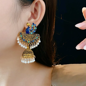 Macro side view of vintage peacock Jhumka earrings with blue enamel and white pearls
