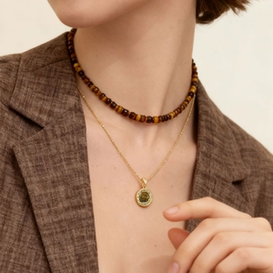 Tiger eye beaded necklace and gold pendant set worn by a model in a brown blazer
