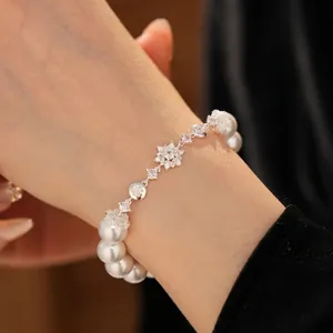 Elegant pearl bracelet featuring zircon flower pendants and a polished silver finish