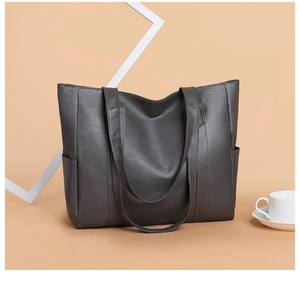 Detail view of large grey PU leather tote bag with side pockets and top handles