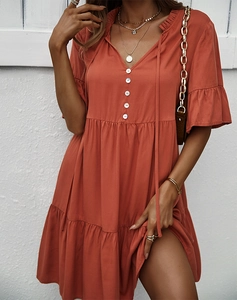 Détail d'une robe rouge orange à col en V avec manches à volants et boutons décoratifs