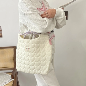 Détail du cabas blanc matelassé en forme de cœur avec anses en corde et étiquette logo