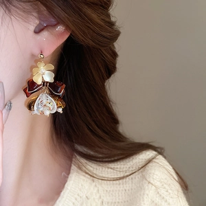 Détail de boucle d'oreille fleur vintage avec nœud et goutte en résine ambrée sur modèle