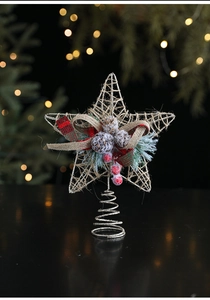 Close-up of golden wire star tree topper with pine cones, berries and ribbon detail