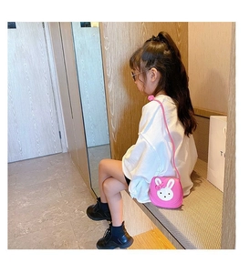 Detail of pink PU leather rabbit crossbody bag worn by a young girl in a modern setting