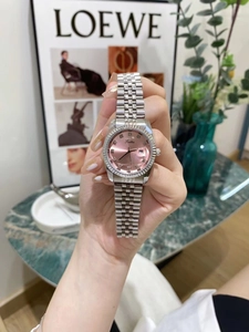 Detail of silver steel watch with pink sunray dial and rhinestone markers on wrist