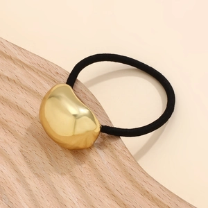 Detailed shot of a sleek golden bean metal charm on a black elastic hair band