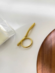 Détail macro d'une barre métallique ondulée plaquée or 18 carats sur une bague minimaliste