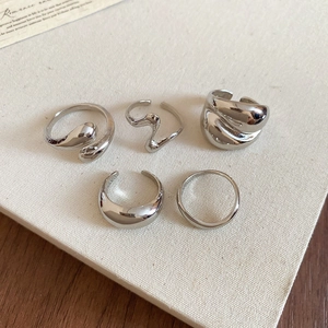 Macro shot of a five-piece silver minimalist ring set with irregular geometric designs