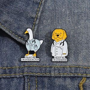 Creative Duckctor and Dogtor enamel pins set pinned on a dark blue denim jacket
