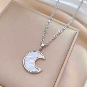 Macro detail of a silver moon pendant with shimmering shell inlay on a jewelry box