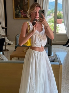 Summer resort style white two-piece set with a crop top and high-waisted pleated maxi skirt