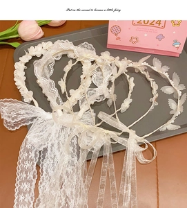 Close-up of white lace hairbands with pearls and ribbons on a display tray