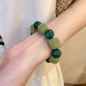 Détail d'un bracelet en perles avec texture malachite vert foncé et perles de résine vert clair