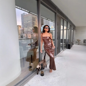Brown sequin one-shoulder evening gown with side slit shown on high-rise city balcony