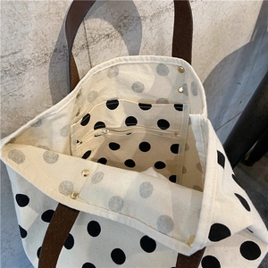 Close-up of polka dot canvas tote with inner zipper pocket and brown leather handle