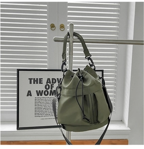 Detail of army green nylon bucket bag featuring a black drawstring and hardware