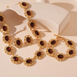 Vintage gold jewelry set with deep red oval gems and white enamel flowers on stone pedestals