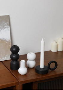 Minimalist matte ceramic candle holders and vases set on a dark wooden surface in home decor