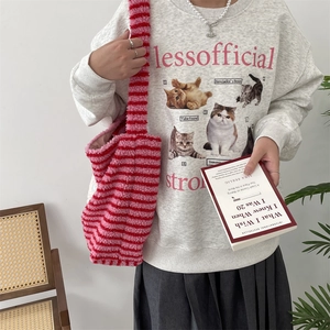 Detail of red and pink striped plush tote bag paired with a printed grey sweatshirt