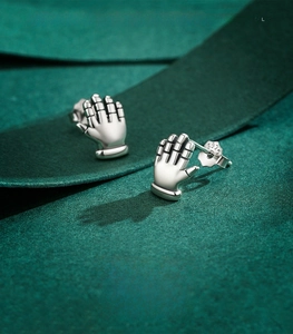 Macro shot of S925 sterling silver robot hand stud earrings on green velvet