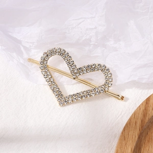 Elegant gold heart-shaped hair clip with sparkling rhinestones on white background