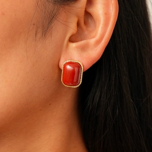 Boucle d'oreille ovale rouge foncé rétro avec bordure dorée torsadée sur un mannequin