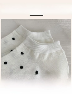 Macro detail of high-elasticity ribbed cuff and black polka dot pattern on white cotton socks