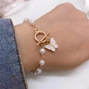Macro view of a pearl bracelet with a white butterfly pendant and golden OT toggle clasp