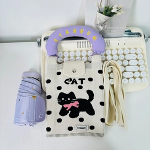 Detail of knitted cat phone bag with polka dots and purple handle on a vintage typewriter