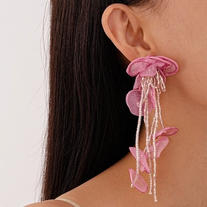 Close-up of pink handmade lace flower earrings with beaded tassels on a model