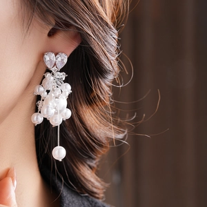 Macro view of crystal heart tassel earrings and white pearls on a female model