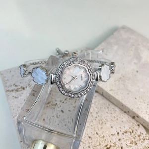 Detailed macro view of a floral clover quartz watch with mother of pearl dial and crystal inlay