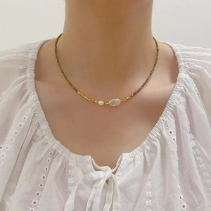 Macro shot of freshwater pearls and golden beads on a minimalist choker necklace