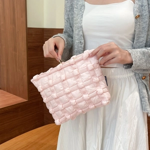 Close-up of pink quilted bubble puffy makeup bag with textured woven canvas and metal zipper