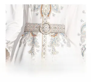 Dettaglio dell'abito bianco con stampa paisley e cintura in vita con fibbia rotonda