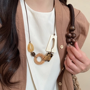 Detail of bohemian necklace with wood beads, rattan circle, and resin geometric pendants