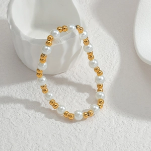 Detail eines Perlenarmband-Sets mit weißen Perlen und Goldakzenten auf Keramik