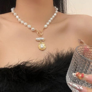Detail of elegant pearl necklace featuring a gold geometric pendant and stylish T-bar clasp