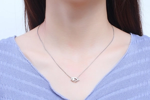 Silver evil eye pendant necklace worn by a model in a high-quality close-up view