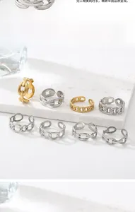 Close-up of 18k gold and silver plated chain-link adjustable rings on a white stone pedestal