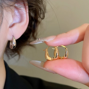 Detailed comparison of 18K gold and silver U-shaped hoop earrings on hand and ear