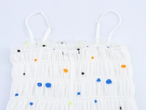 Dettaglio dell'abito in rete bianca con corpetto a punto smock e ricami floreali 3D