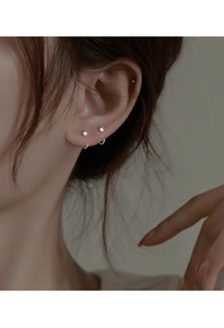 Close-up of S925 sterling silver zircon stud and hoop earrings on model ear lobe