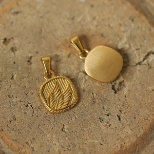 Macro view of gold-plated titanium steel pendants with vintage relief on stone surface
