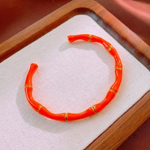 Dettaglio del bracciale a forma di bambù in smalto arancione con accenti dorati