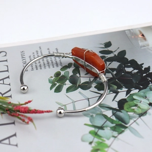 Detailed view of silver wire-wrapped orange crystal stone on an open bangle bracelet