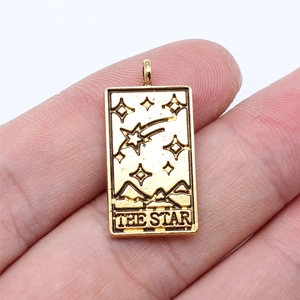 Detailed macro view of The Star tarot card pendant held by hand for size reference